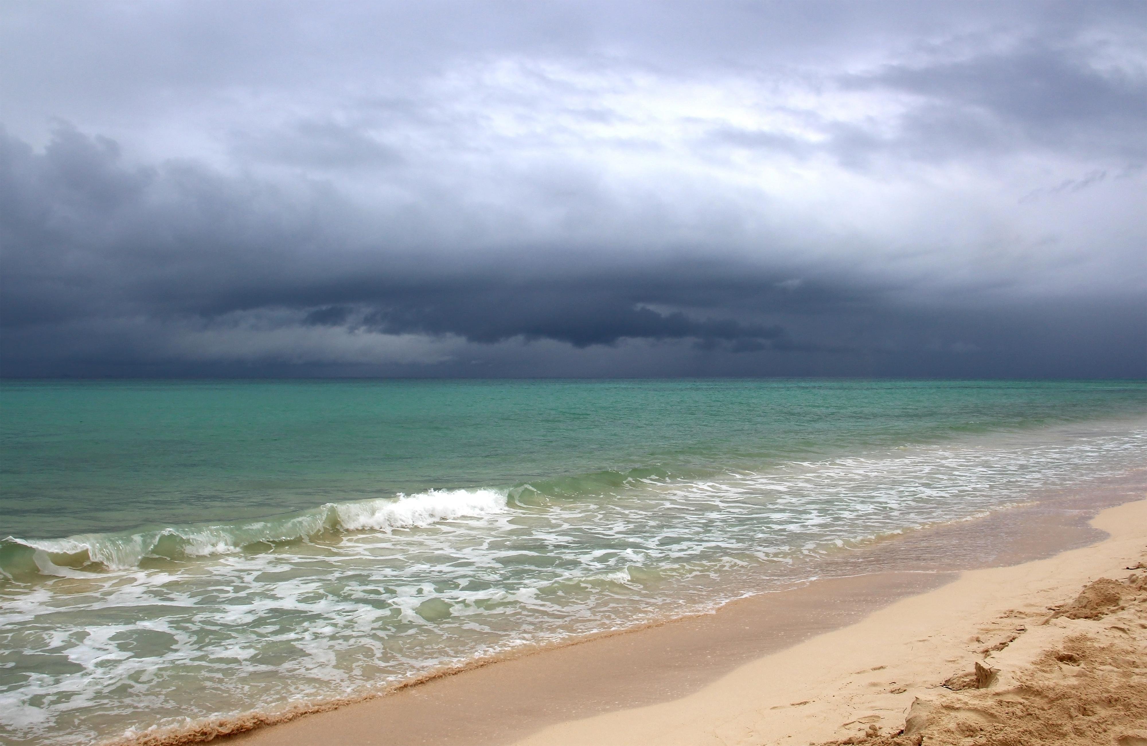 Storm clouds gathering over calm turquoise water on a Los Cabos beach during hurricane season